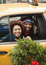 African couple riding in taxi with Christmas wreath