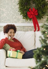 Mixed race woman holding Christmas presents talking on telephone