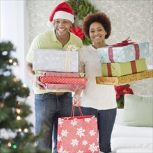 African couple holding stacks of Christmas presents