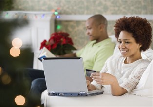 Mixed race woman buying Christmas presents online with credit card