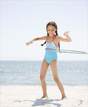 Hispanic girl playing with plastic hoop on beach
