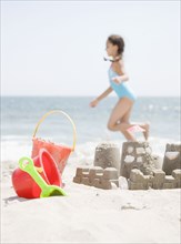 Hispanic girl and sand castle on beach