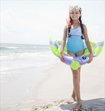 Hispanic girl with inflatable ring on beach