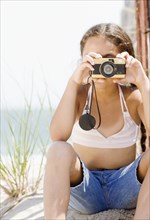 Hispanic girl taking photograph on beach