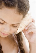 Hispanic girl listening to seashell