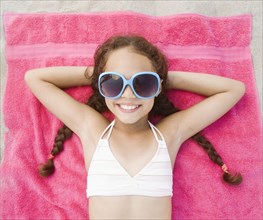 Hispanic girl laying on beach in bikini and sunglasses