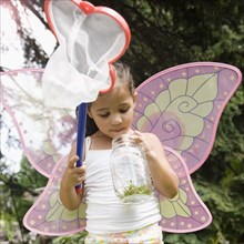 Hispanic girl in butterfly costume with jar