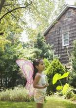 Hispanic girl in butterfly costume with jar