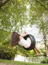 Hispanic girl swinging on tire swing