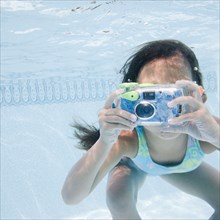 Hispanic girl taking photograph underwater