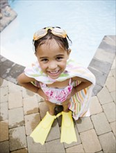 Hispanic girl standing at poolside in flippers