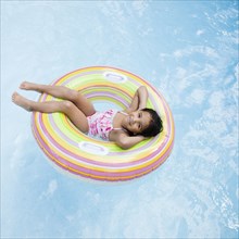 Hispanic girl floating in pool in inflatable ring