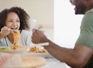 African father and daughter eating pasta