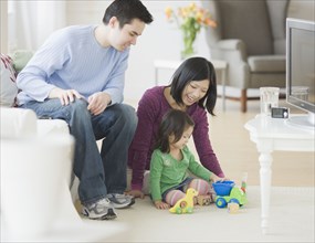 Mother and father playing with daughter in livingroom