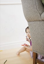 Toddler girl hiding behind chair