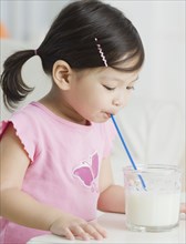 Mixed race girl drinking milk with straw