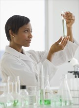 African scientist looking at vial of liquid