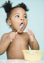 African American girl trying to eat cereal with spoon