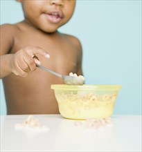 African American girl eating cereal with spoon