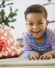 African American boy laying on floor by Christmas tree
