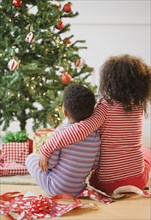 African American brother and sister hugging by Christmas tree