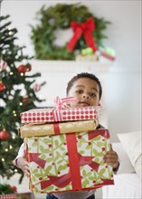 African American boy holding stack of Christmas gifts