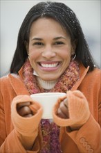 Mixed race woman drinking coffee in snow
