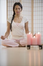 Mixed race woman meditating in lotus pose