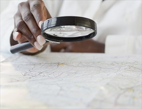 African woman using magnifying glass on map