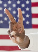 African woman making peace symbol near American flag