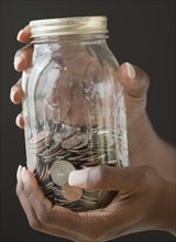 African woman holding jar of coins