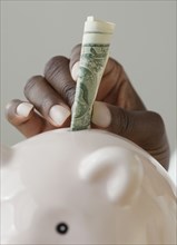 African woman putting money in piggy bank