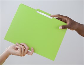 African woman handing co-worker a folder