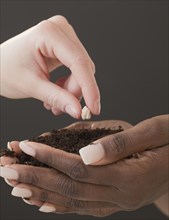 Woman planting seed in handful of soil