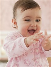 Mixed race baby girl with hands out laughing
