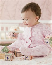 Mixed race baby girl playing with alphabet blocks