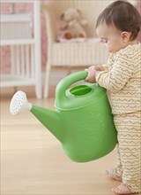 Mixed race baby girl holding watering can