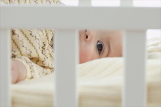 Mixed race baby girl laying in crib