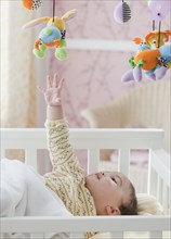 Mixed race baby girl reaching for toy mobile