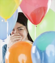Hispanic woman laughing behind balloons