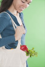 Hispanic woman carrying reusable bag of vegetables