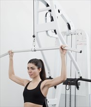 Hispanic woman using weight machine in health club
