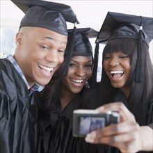 African friends in graduation cap and gown taking self-portrait