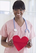 African nurse holding heart-shaped piece of paper