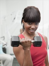 African woman using hand weight in health club