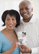 African couple holding photo of granddaughter