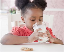 African girl drinking milk with cookie