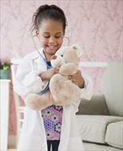 African girl playing doctor with teddy bear