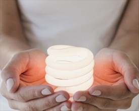 Woman holding glowing compact fluorescent bulb