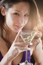 Mixed race woman drinking martini with olives